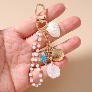 Detail of ocean-themed keychain with pearls, gold shells, and blue starfish pendant