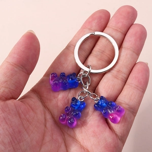 Detailed view of triple gradient resin bear charms on a silver keychain held by hand