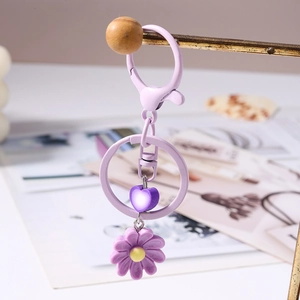 Dettaglio del portachiavi con margherita viola e ciondolo a cuore sfumato