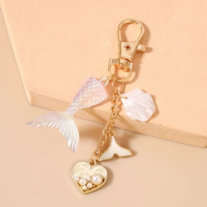 Macro detail of ocean-themed mermaid tail shell and pearl heart keychain charms