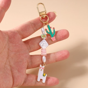 Macro view of cactus and alpaca keychain charms with colorful beads held in hand