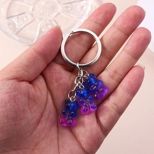 Macro detail of three gradient resin gummy bear charms on a silver metal keychain