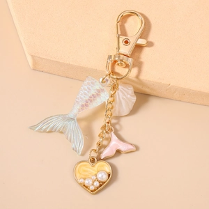 Detail of ocean-themed keychain with iridescent fishtail, shell and pearl heart charm
