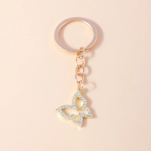 Porte-clés papillon ajouré en or rose avec strass brillants sur fond rose élégant