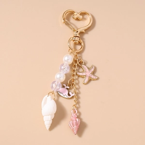 Detail of gold heart clasp with pearl beads and pink enamel ocean-themed charms
