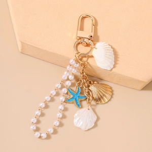 Detail of nautical keychain with blue glitter starfish, golden shells, and pearls