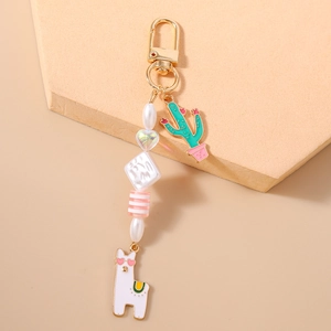 Detail of cute llama and cactus charms on a golden keychain with colorful beads