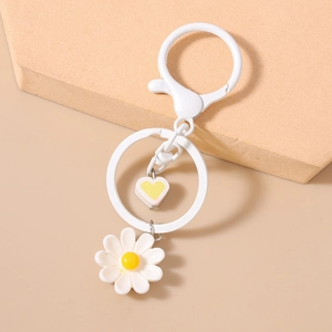 Dettaglio del portachiavi a margherita bianca con pendente a cuore e anello metallico