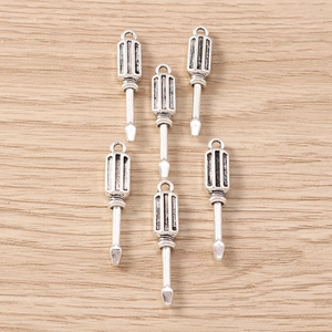 Set of 6 silver screwdriver pendants for DIY jewelry making on wooden background