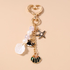 Detail of marine-themed keychain with gold heart clasp, sea shell, whale, and starfish charms
