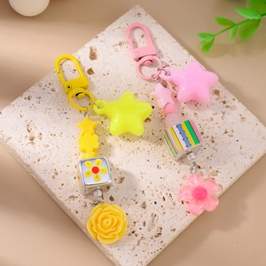 Detail of candy-colored keychains with resin stars, flowers, and striped cubes on stone