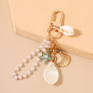 Close-up of ocean-themed keychain with gold starfish, seashell charms and white pearls