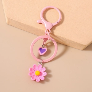 Dettaglio del portachiavi a margherita rosa con ciondolo a cuore viola e moschettone