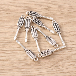 Macro shot of vintage silver screwdriver charms on a light wood surface for jewelry making