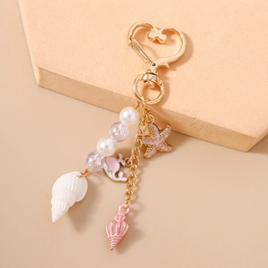 Detail of beaded whale tail and starfish ocean keychain with a gold heart clasp