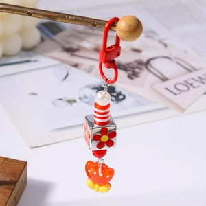 Dettaglio di un portachiavi vivace con cubo a fiori e ciondolo a farfalla arancione