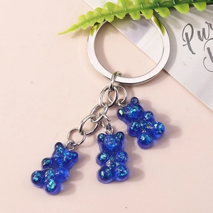 Detail of three blue glitter resin gummy bears on a silver metal keychain charm