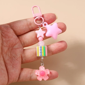 Close-up of pink star and flower charms keychain held in hand with cube bead detail