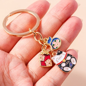 Japanischer Maneki-neko Glückskatzen-Schlüsselanhänger mit roten und blauen Omamori-Anhängern