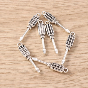 Macro shot of 6 vintage silver screwdriver charms for jewelry making on wooden background