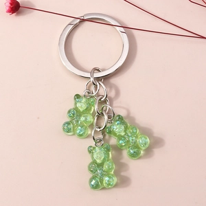 Detail of three green gummy bear charms with glitter inside on a silver metal keychain