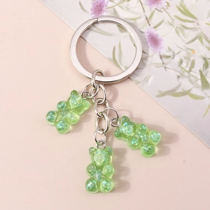 Detail of three green translucent resin gummy bears with glitter on a silver keychain ring