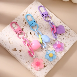 Colorful macaron heart and flower keychains with chunky plastic chains on stone plate