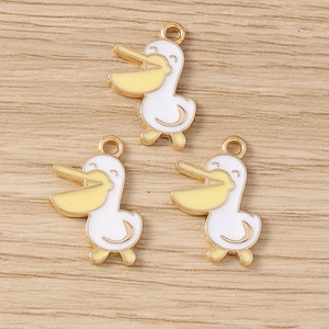 Vue macro de trois breloques en émail de pélican blanc et jaune avec contours dorés