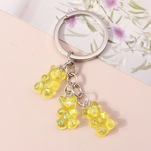 Macro detail of three yellow glitter resin bears attached to a silver keychain link