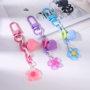 Three colorful acrylic heart and flower keychains in pink, purple, and blue candy tones