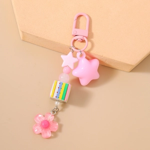 Close-up of pink beaded keychain with star, rainbow cube, and flower charms on a stand
