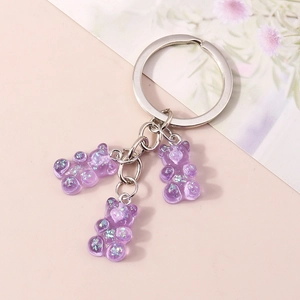 Detail of three purple resin gummy bears with colorful laser glitter on silver keychain