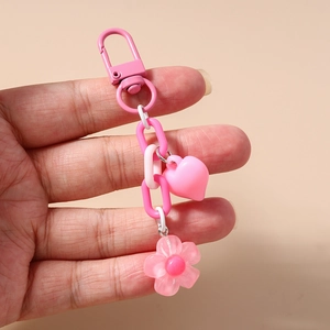 Pink heart and flower keychain held in hand with pastel plastic chain and metal clasp