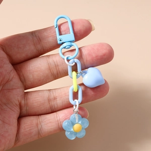 Detail of blue heart and flower keychain held by hand for bags and keys