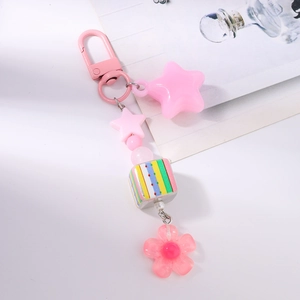 Close-up of pink beaded keychain with stars, resin flower, and striped cube charm on a D-clasp