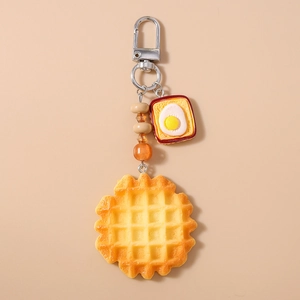 Detail of beaded food keychain with realistic yellow waffle and egg toast charms