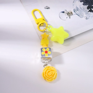 Detail of yellow flower and star charm keychain with engraved cube bead pendant