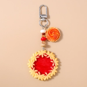 Close-up of artificial strawberry pie keychain with colorful beads and silver lobster clasp