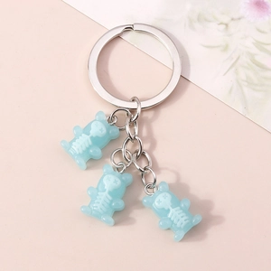 Detailed view of light blue skeleton bear pendants with silver metal keyring on pink background
