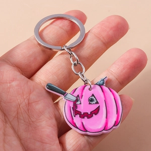 Detail of pink pumpkin keychain with acrylic spooky knife design and silver ring