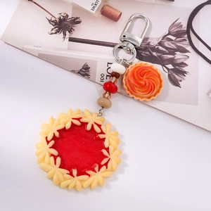 Detail view of simulated food keychain with red jam tart and orange swirl cookie charms