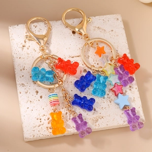 Colorful resin gummy bear keychain with gold star and striped beads on stone background