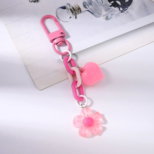 Close-up of pink heart and sakura flower charms on a stylish acrylic keychain chain