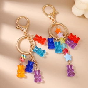 Colorful resin bear and star keychains with gold metal rings on a minimalist white background