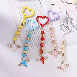 Close-up of colorful beaded heart keychains with winged cross pendants and floral beads