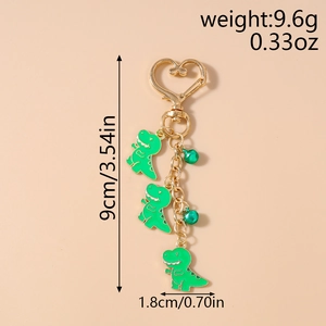 Detail view of cartoon dinosaur keychain with golden heart clasp and green bells