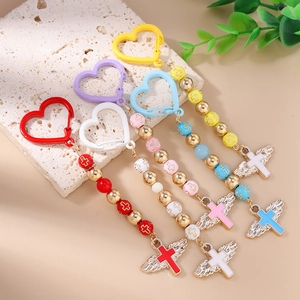 Cross and wing beaded keychains in five colors on a textured stone surface
