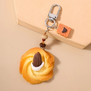 Close-up of butter cookie and mini toast keychain with brown beads on stone display