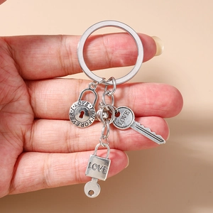 Retro silver metal keychain with LOVE lock and key charms held in hand for scale