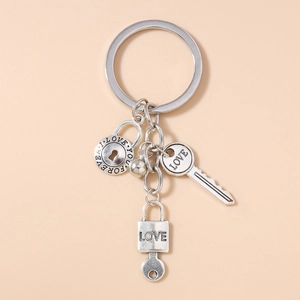 Detail of silver LOVE key keychain featuring engraved heart lock and round charm